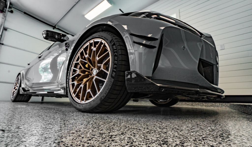 BMW parked in a home garage with sleek, glossy Penntek-coated floors, showcasing a durable and stylish concrete coating finish.