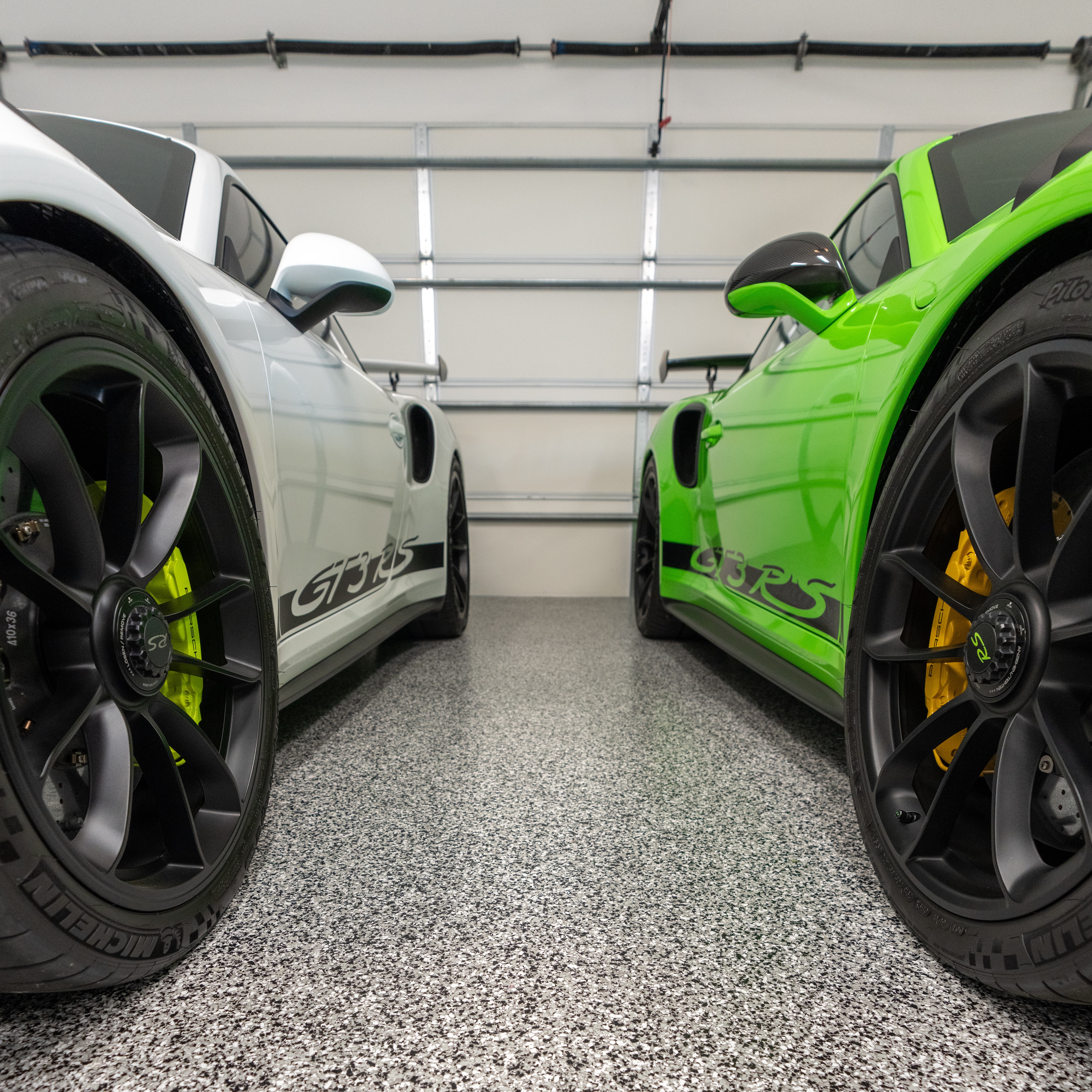 A white and lime green Porsche parked in a local garage with Penntek-coated floors, featuring a glossy, durable concrete finish that complements the car's vibrant colors.